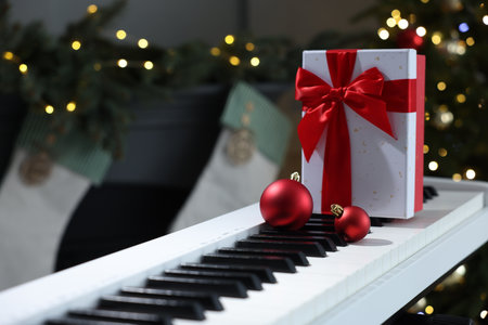 Gift and Christmas ornaments on piano against blurred lights, closeup. Bokeh effectの写真素材