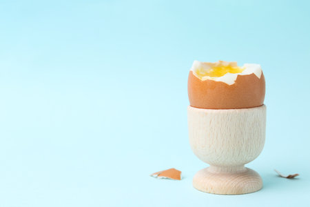 Soft boiled egg in eggcup on light blue background, closeup. Space for textの写真素材