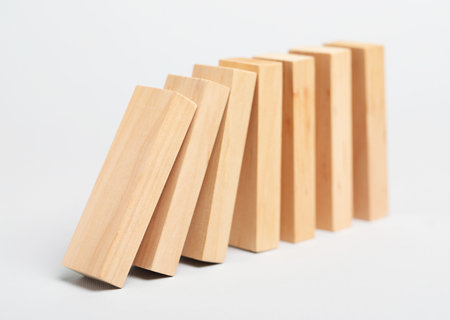 Domino effect. Wooden blocks falling on light backgroundの写真素材