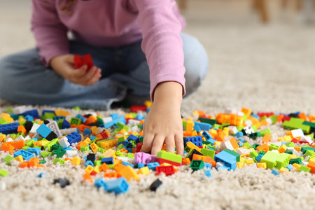 Girl playing with building blocks on floor at home, closeupの写真素材