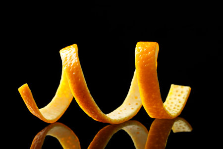 One fresh orange peel on black mirror surface, closeupの写真素材