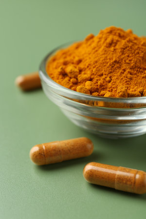 Many turmeric capsules and powder on light green background, closeupの写真素材