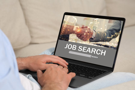 Man looking for job using employment website on laptop at home, closeupの写真素材