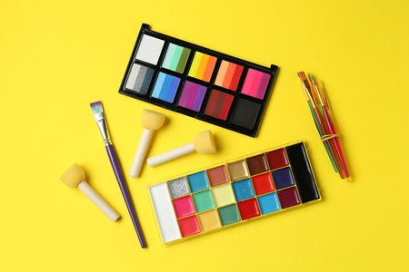 Face paints and tools on yellow background, flat layの写真素材