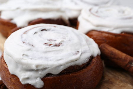 Tasty cinnamon rolls with cream as background, closeup