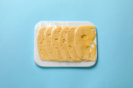 Pack of sliced cheese on light blue background, top viewの写真素材