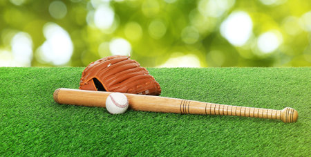 Baseball bat, ball and glove on green grass, banner design. Sports equipment