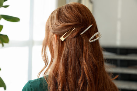Teenage girl with stylish hair clips indoors, back viewの写真素材