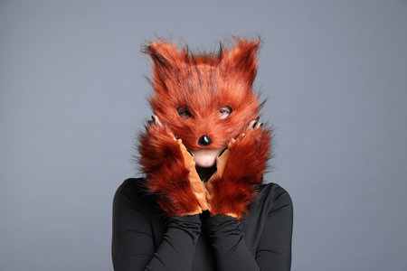 Girl wearing fox mask and gloves on grey backgroundの写真素材