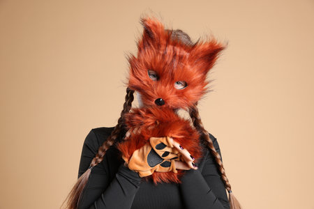 Quadrobics. Girl wearing fox mask and gloves on beige backgroundの写真素材