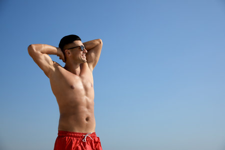 Handsome man with attractive body against blue sky. Space for textの写真素材