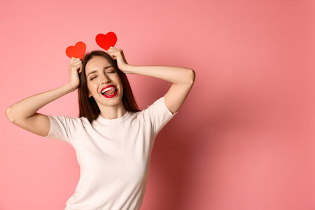 Happy Valentine's Day. Beautiful woman with paper hearts on pink background. Space for textの写真素材