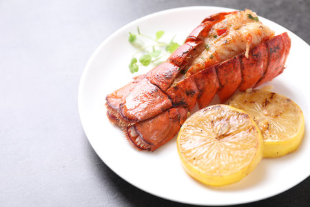 Delicious lobster tail with microgreens and slices of lemon on gray textured table, closeupの写真素材