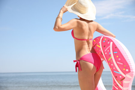 Young woman holding inflatable ring on beach. Space for textの写真素材
