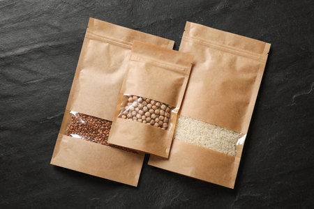 Paper pouch bags with different products on black table, top view