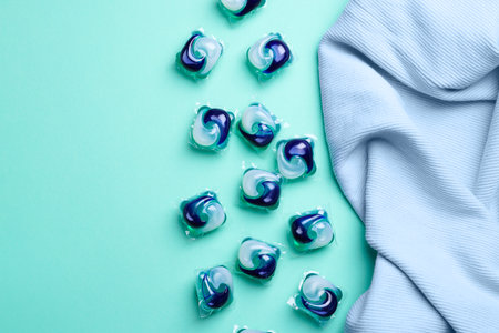 Laundry detergent capsules and clothes on turquoise background, flat layの写真素材