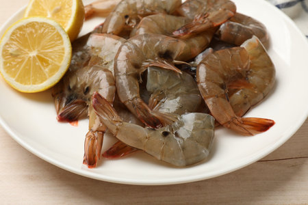 Fresh raw shrimps with lemon on wooden table, closeupの写真素材