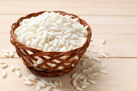 Puffed rice in wicker basket on wooden table, closeup. Space for textの写真素材