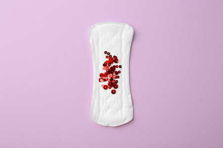 Menstrual pad with sequins on lilac background, top viewの写真素材