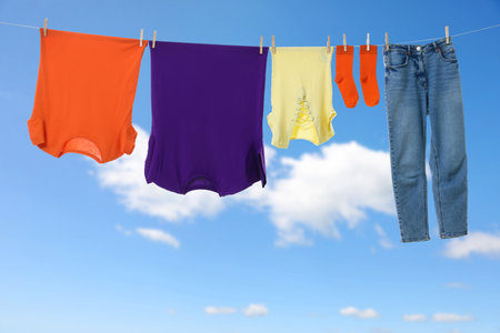 Different clothes drying on washing line against blue skyの写真素材