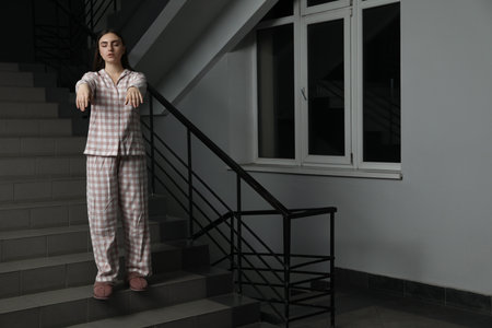 Woman suffering from sleepwalking on stairs indoorsの写真素材