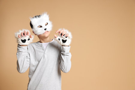 Quadrobics. Boy wearing cat mask and gloves on beige background, space for textの写真素材