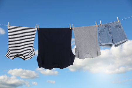 Different clothes drying on washing line against blue skyの写真素材