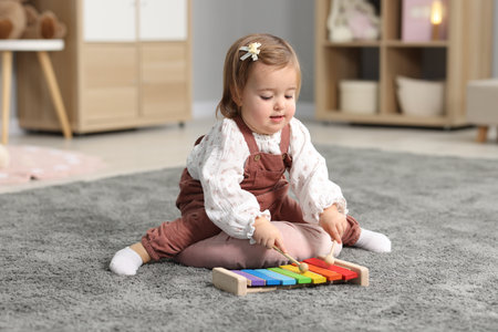 Cute little girl playing with toy on floor at homeの写真素材