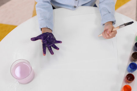 Girl drawing with palm at white table indoors, closeupの写真素材