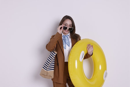 Businesswoman with inflatable ring, bag and sunglasses on white backgroundの写真素材