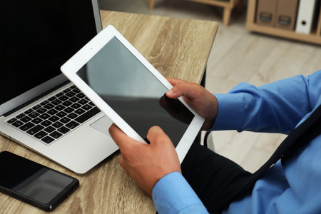 Businessman with tablet, laptop and smartphone at wooden table, closeup. Modern technologyの写真素材