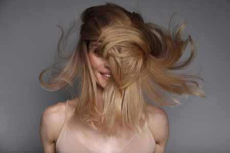 Woman with beautiful blonde hair on grey backgroundの写真素材