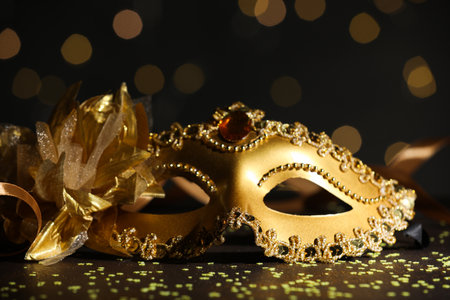 Beautiful carnival mask and confetti on dark background with blurred lights, closeupの写真素材