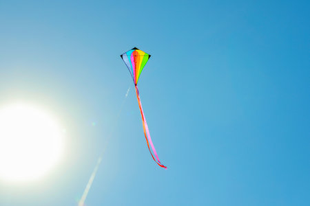 One colorful kite flying in blue sky on sunny day. Space for textの写真素材