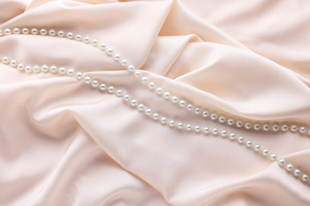 Beautiful pearl necklace on beige cloth, top viewの写真素材