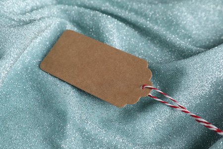 Blank tag with string on teal fabric, closeup