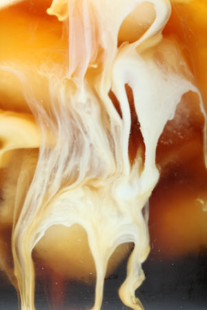 Refreshing coffee with ice and milk as background, closeup