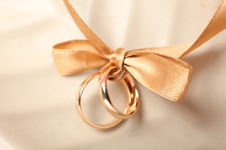 Wedding rings tied with ribbon on beige background, top viewの写真素材