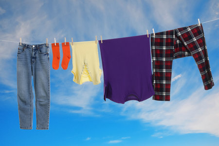 Different clothes drying on washing line against blue skyの写真素材