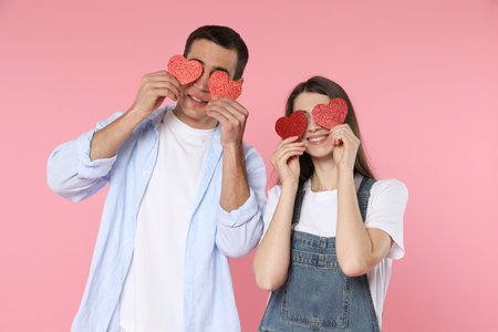 Lovely couple with paper hearts on pink background. Valentine's day celebrationの写真素材