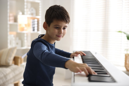 Cute boy playing synthesizer at home. Electronic musical instrumentの写真素材