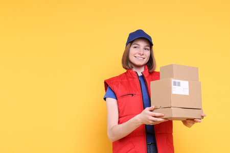 Happy postwoman with parcels on yellow backgroundの写真素材
