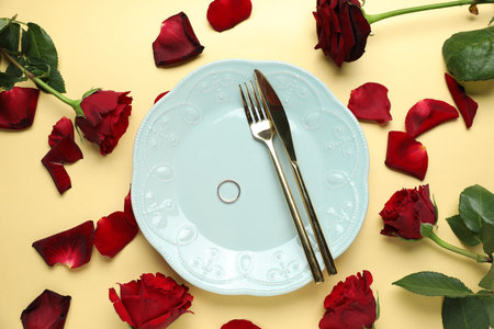 Beautiful setting for romantic dinner, engagement ring and roses on beige background, flat layの写真素材