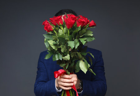 Happy Valentine's Day. Man with bouquet of roses on grey backgroundの写真素材
