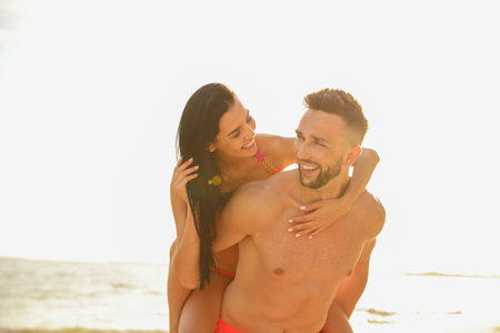 Happy young couple having fun on beach on sunny day