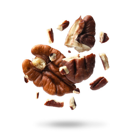 Broken pecan nuts in air on white backgroundの写真素材