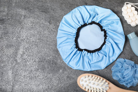 Shower cap and bath accessories on grey background, flat lay. Space for textの写真素材