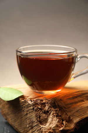 Aromatic black tea in cup and green leaf on wooden snag, closeupの写真素材