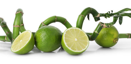 Fresh limes and bamboo stems on mirror surface against white backgroundの写真素材