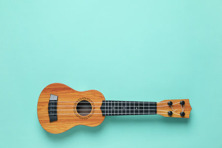 One ukulele on turquoise background, top view. Space for text